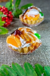 Десерт тарталетка с кремом и фруктами залитыми сладкой карамелью.