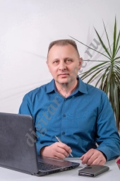 Бизнесмен сидит за своим столом и работает на портативном компьютере.