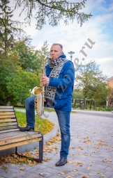 Мужчина с саксофоном на улице осенью