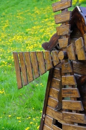 Декоративная деревянная мельница на фоне зеленой лужайки.