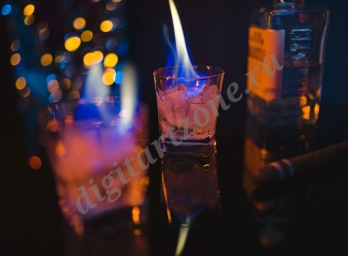 Огонь в стаканах с крепким алкоголем на барной стойке.