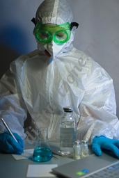 Медик в анти-ковидном костюме в лаборатории перед компьютером.