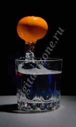 Застывшая вода; стакан с яркими бликами и застывший в падении мандарин
