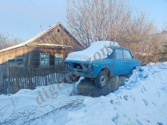 Старые Жигули в снегу на пьедестале в деревне