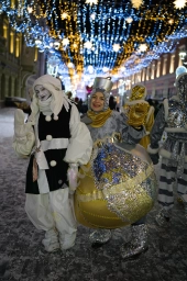 Весёлые персонажи Новогоднего карнавала в свете праздничных огней.