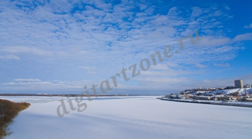 Зимний пейзаж с видом на замерзшую, заснеженную реку и речной порт.